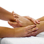 Young African American woman getting a foot massage and isolated on a white background
